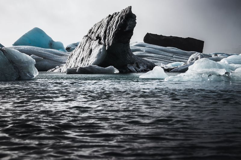 A dark, ash-streaked iceberg rising from choppy grey water