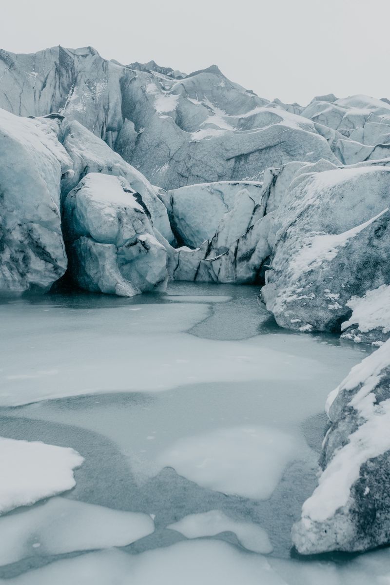 A frozen pool surrounded by snow-covered glacier ice