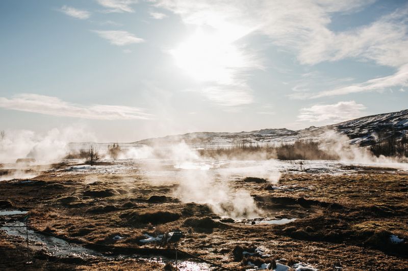 Steam rising from hot springs in the Geysir field on a sunny winter day