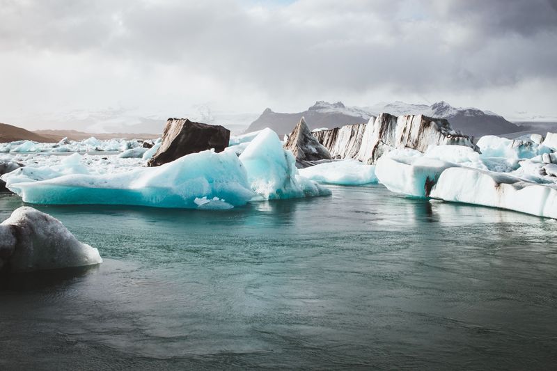 Blue and ash-striped icebergs in Jökulsárlón glacier lagoon under a stormy sky