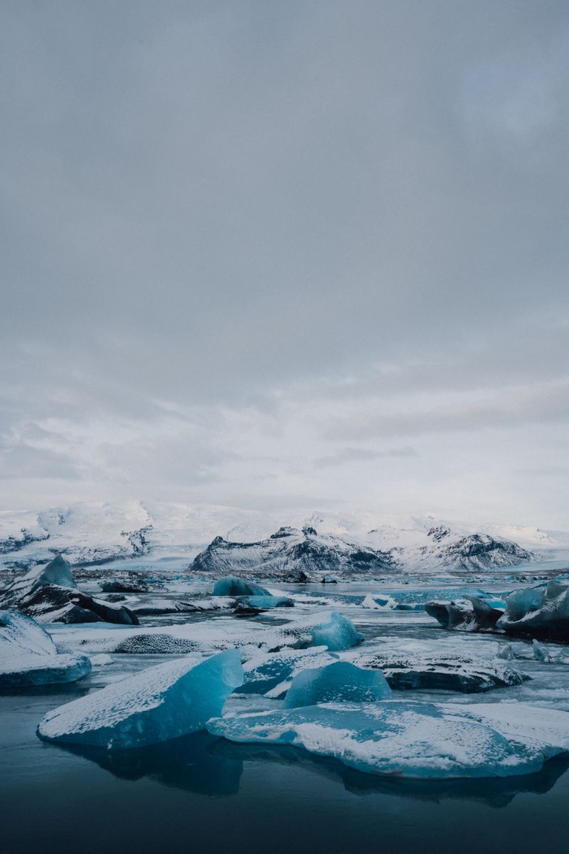 Snow-dusted blue icebergs in Jökulsárlón below white mountains