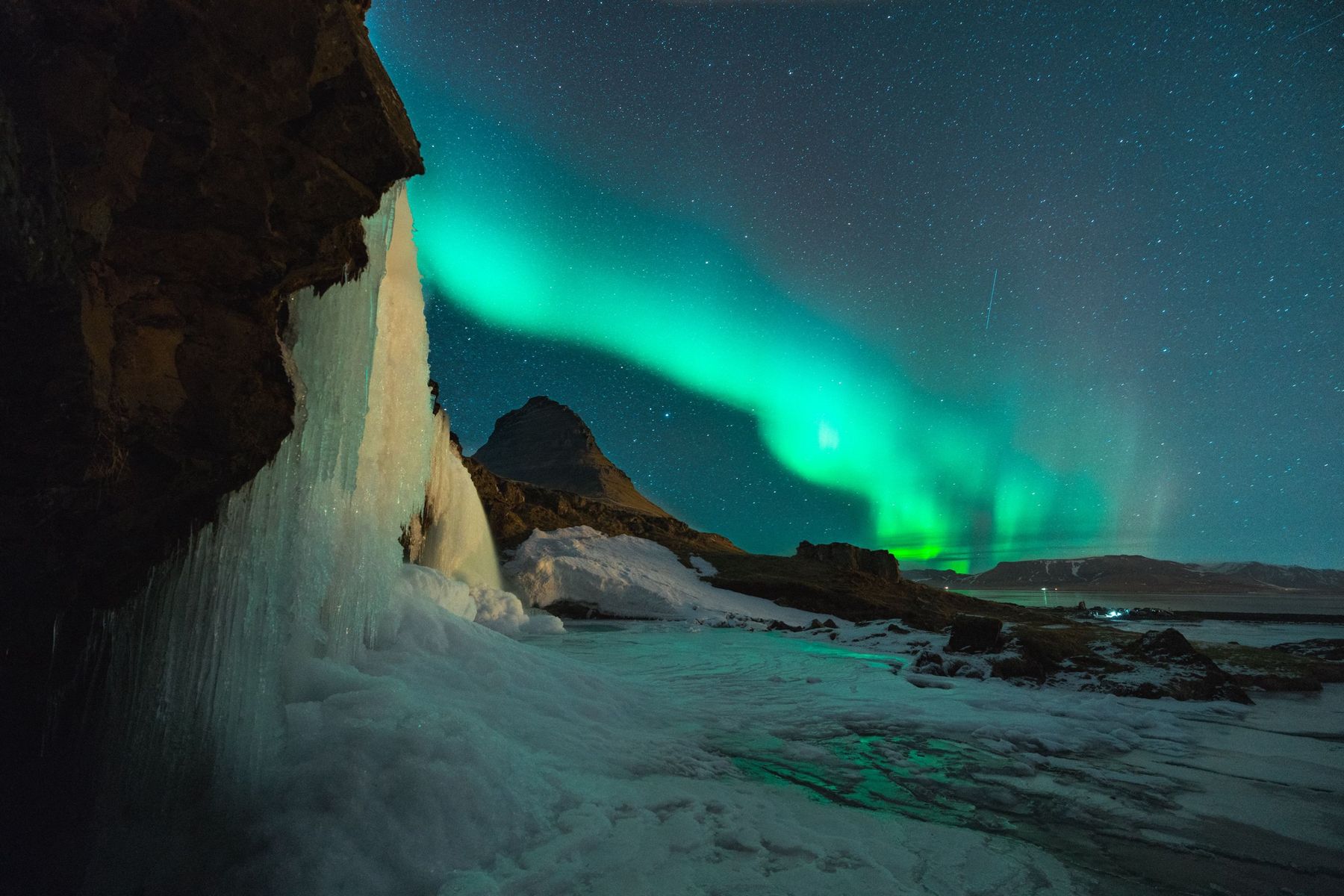 Northern lights over Kirkjufell mountain and a frozen waterfall