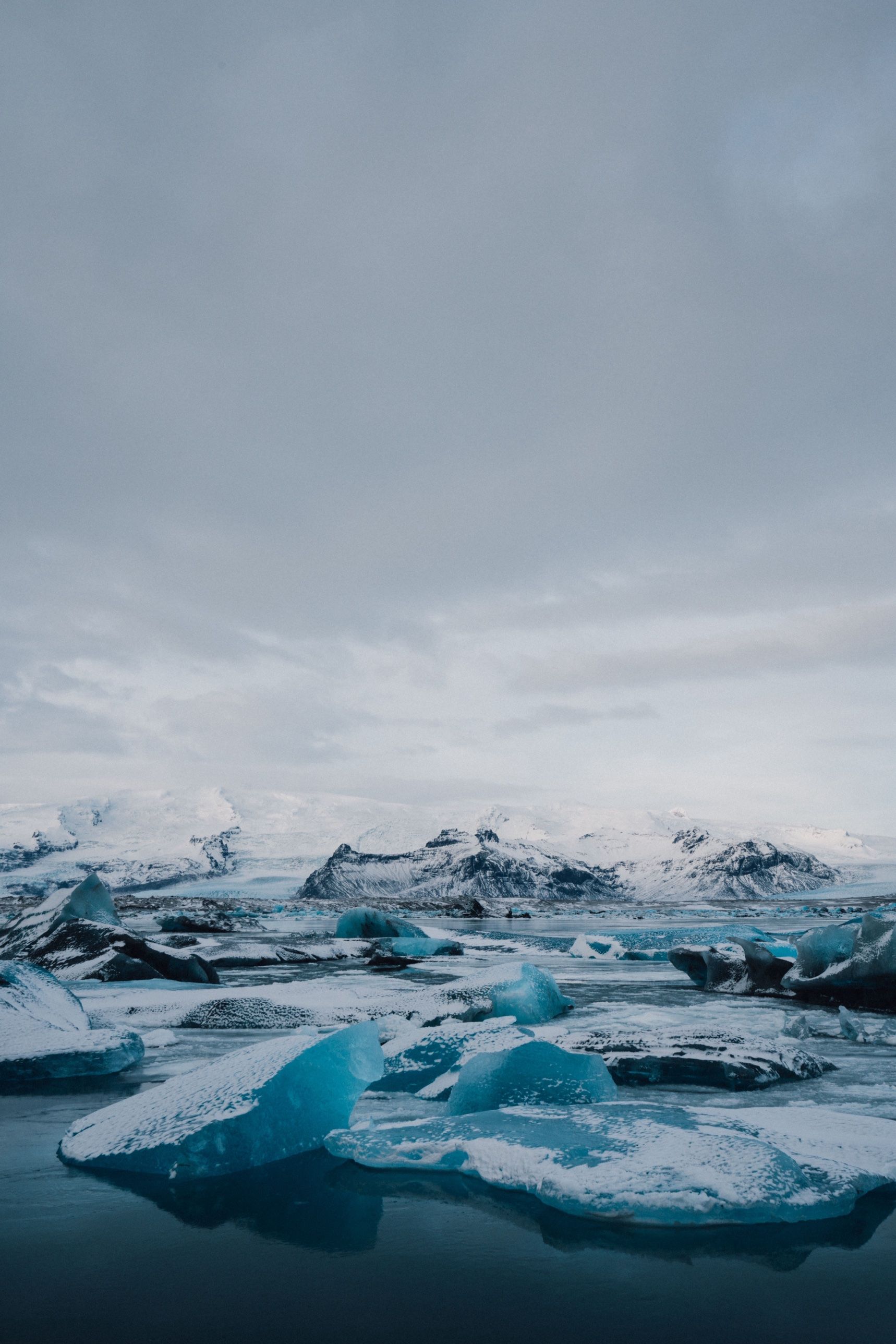 Snow-dusted blue icebergs in Jökulsárlón lagoon below white mountains